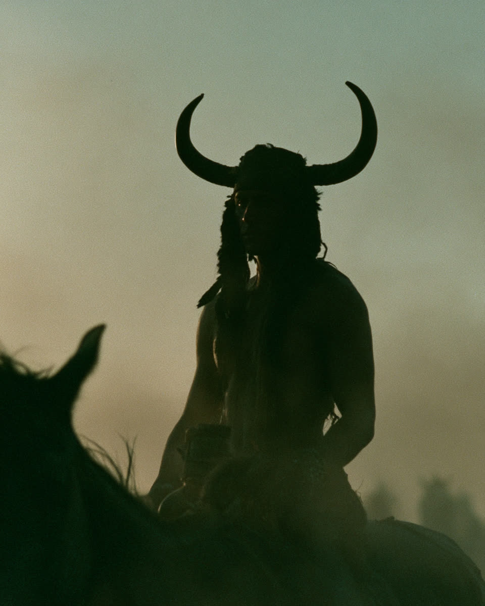 A horned silhouette on horseback in low fog.